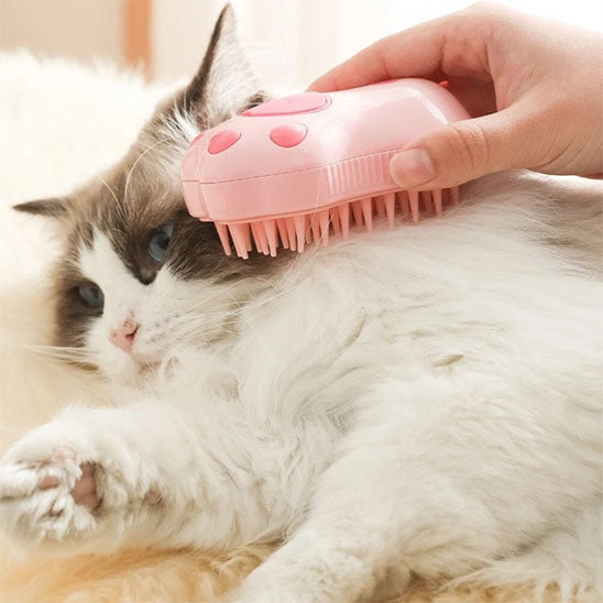Brosse pour chat rose utilisée sur le cou d’un chat blanc et gris à poils longs.